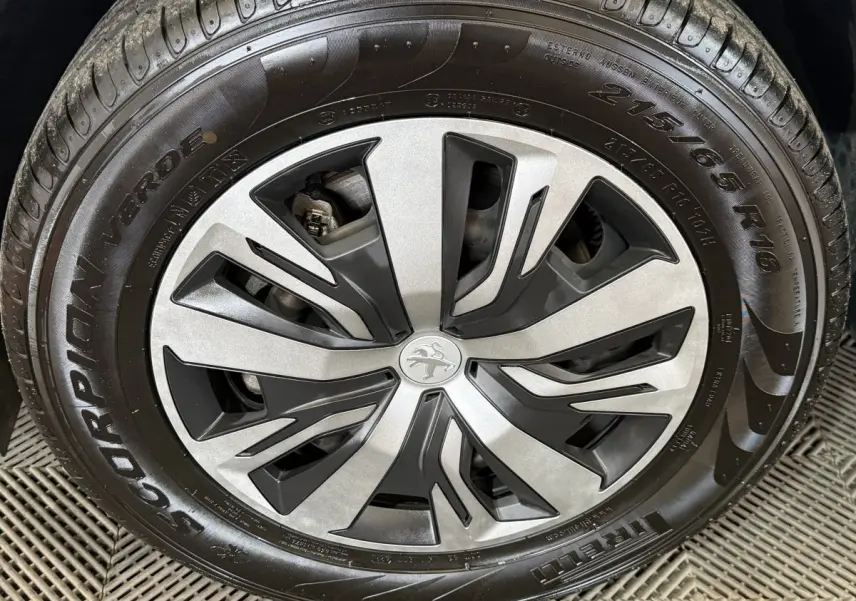 Gros plan sur la jante alliage argent et noir du Peugeot 2008 blanc, mettant en valeur le logo lion central.