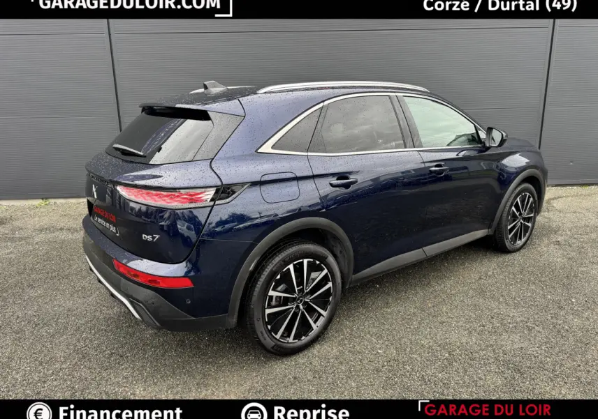 Vue 3/4 arrière droite d’un DS7 Crossback bleu foncé 2024 avec jantes alliage noires et feux arrière LED distinctifs.