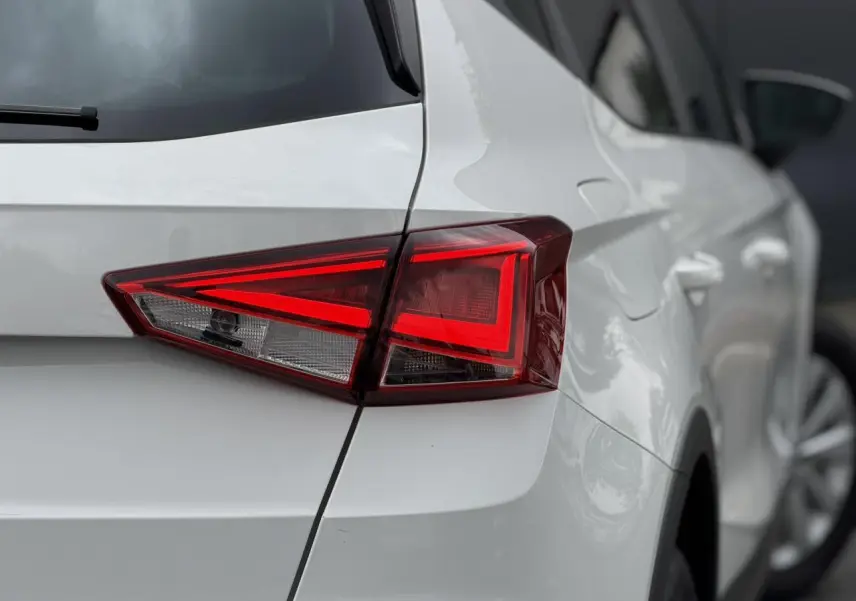 Gros plan sur le feu arrière droit d'un SEAT Arona blanc, mettant en valeur la ligne anguleuse et la carrosserie lisse.