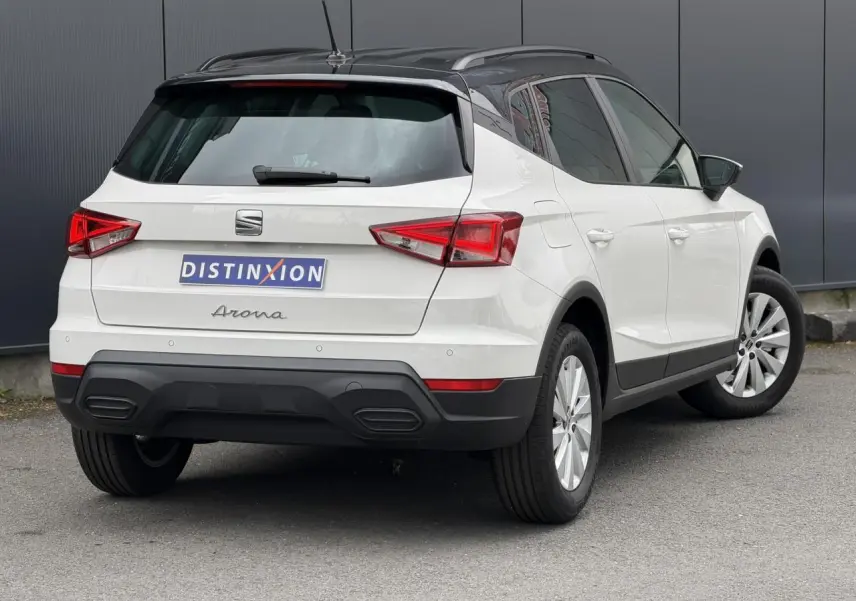 Vue 3/4 arrière droite d'un SEAT Arona blanc avec toit noir contrasté et jantes alliage 16 pouces.