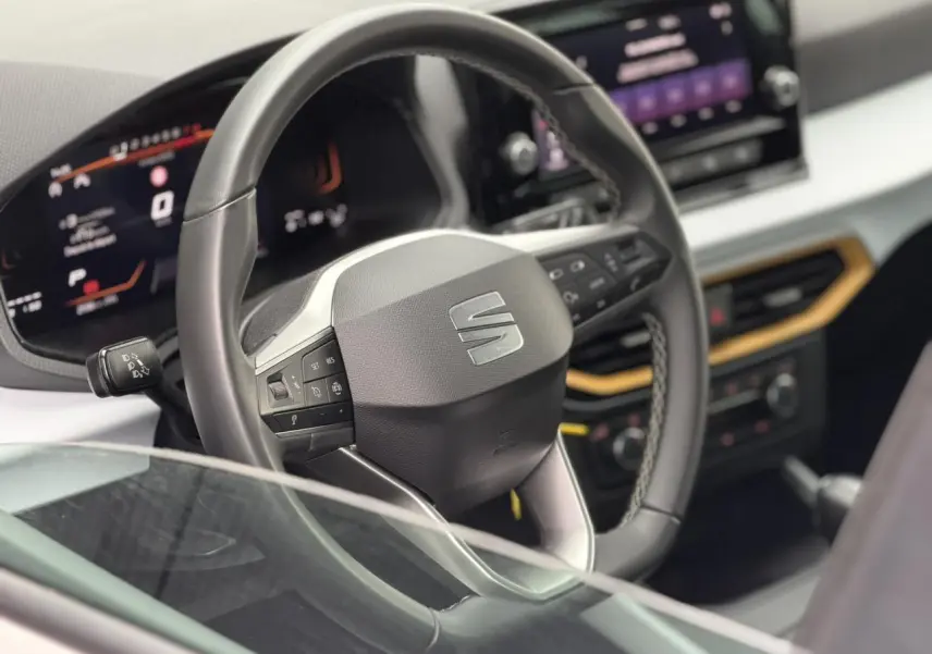 Vue rapprochée du volant et du tableau de bord digital du SEAT Arona TSI 115 DSG Style avec écran tactile et finitions modernes.