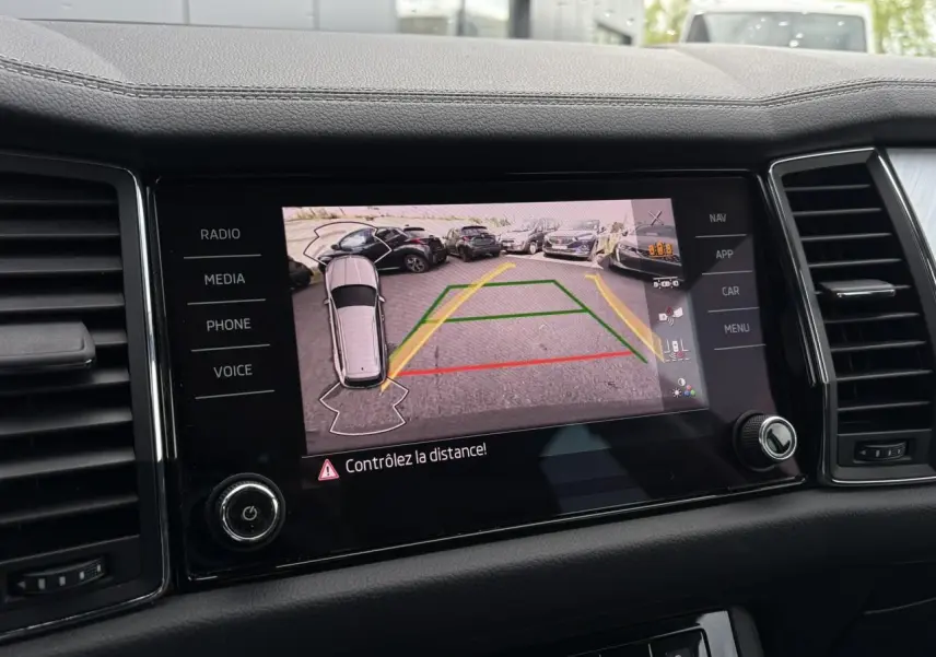 Écran central du Skoda Kodiaq 2024 affichant la caméra de recul avec vue aérienne et lignes de guidage.
