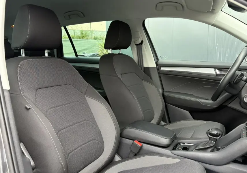 Vue intérieure côté avant droit du Skoda Kodiaq 2024, sièges tissu gris foncé avec accoudoir central noir.