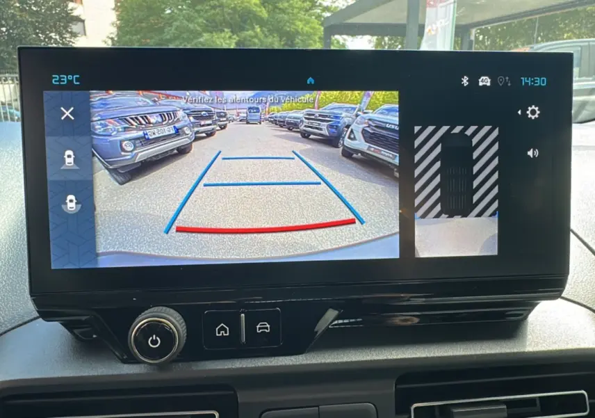 Vue intérieure du tableau de bord du Citroën Berlingo 2025 avec écran affichant la caméra de recul et les aides au stationnement.