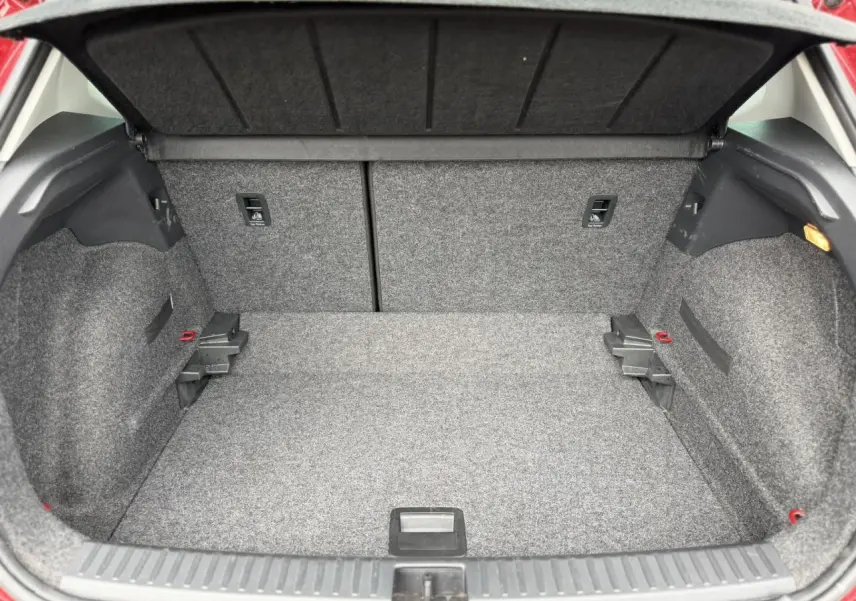 Vue intérieure du coffre spacieux et tapissé de moquette grise du SEAT Arona Rouge Désir, avec la plage arrière relevée.