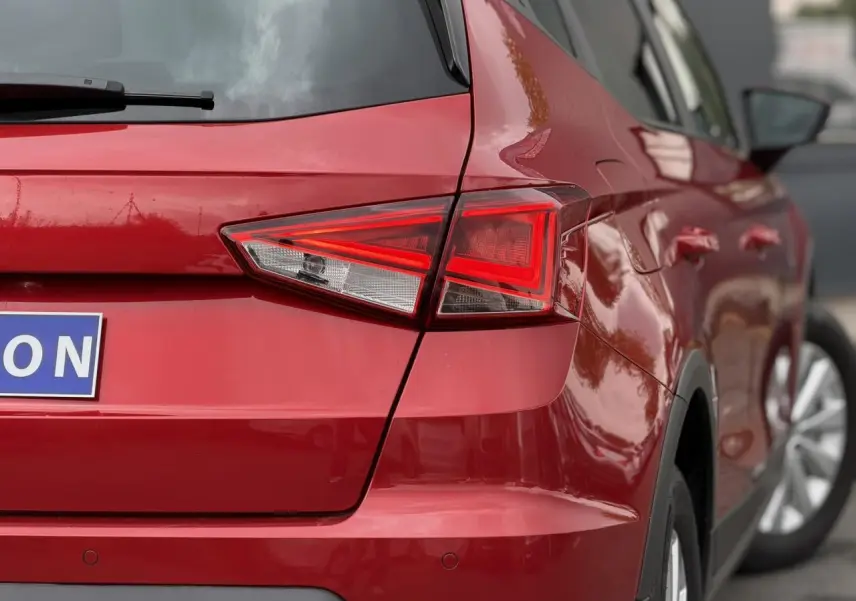 Vue arrière droite d’un SEAT Arona rouge Désir avec feux arrière LED et jantes alliage visibles.
