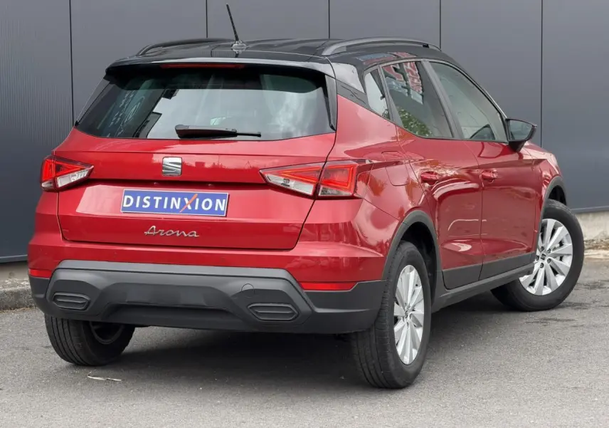 Vue 3/4 arrière droite d’un SEAT Arona rouge Désir avec toit noir et jantes alliage 16 pouces.