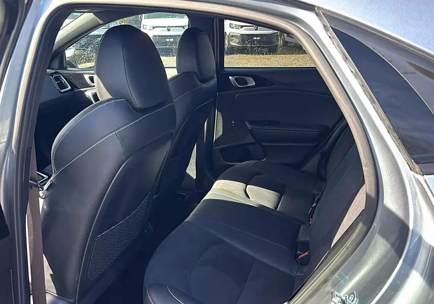 Vue intérieure arrière côté droit du Kia Xceed gris 2024, sièges en tissu noir avec appuie-têtes et rangements au dos des sièges avant.