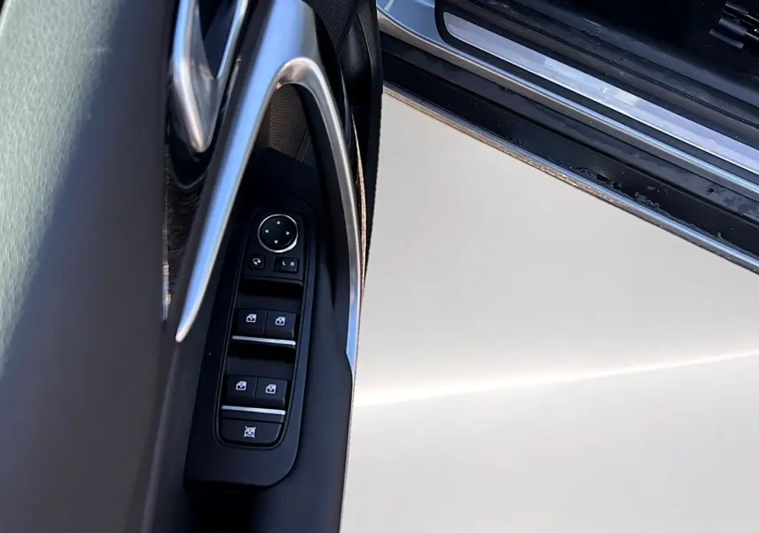 Détail de la porte côté gauche d’une KIA Xceed gris 2024, avec commandes électriques des vitres et rétroviseurs.