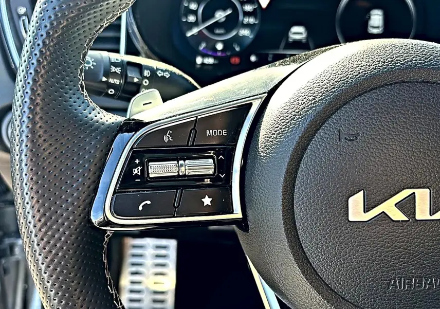 Gros plan sur le volant cuir perforé côté gauche du Kia Xceed gris, avec commandes multifonctions et palettes au volant.