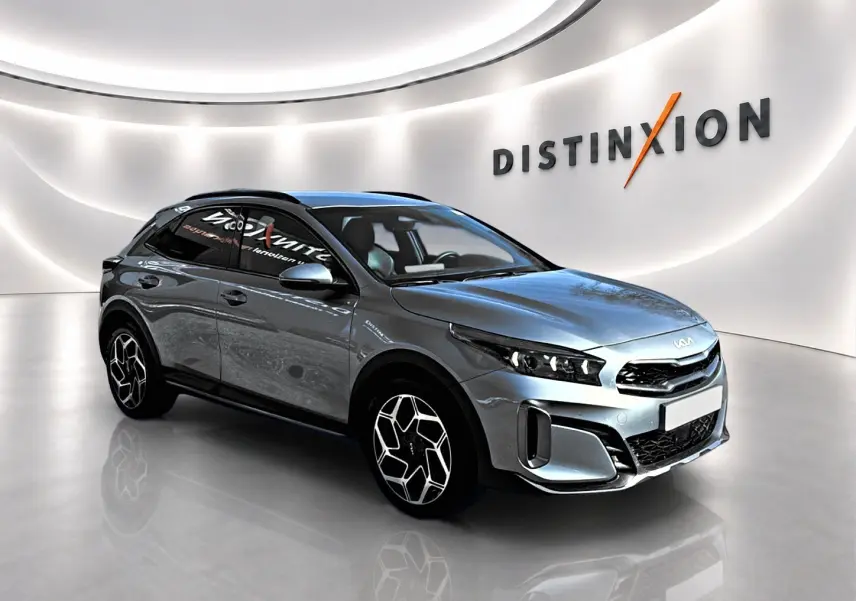 Kia Xceed gris en vue 3/4 avant droit, avec jantes alu et calandre chromée dans un showroom lumineux.