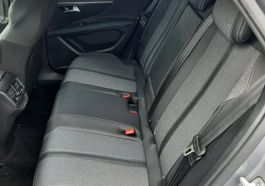 Vue intérieure côté droit sur la banquette arrière en tissu gris et cuir noir du Peugeot 3008 Hybrid 2024.
