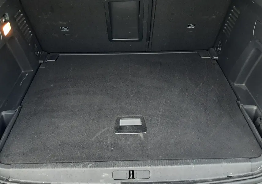 Coffre spacieux ouvert du Peugeot 3008 Hybrid gris Artense, montrant le plancher plat et les parois intérieures noires.