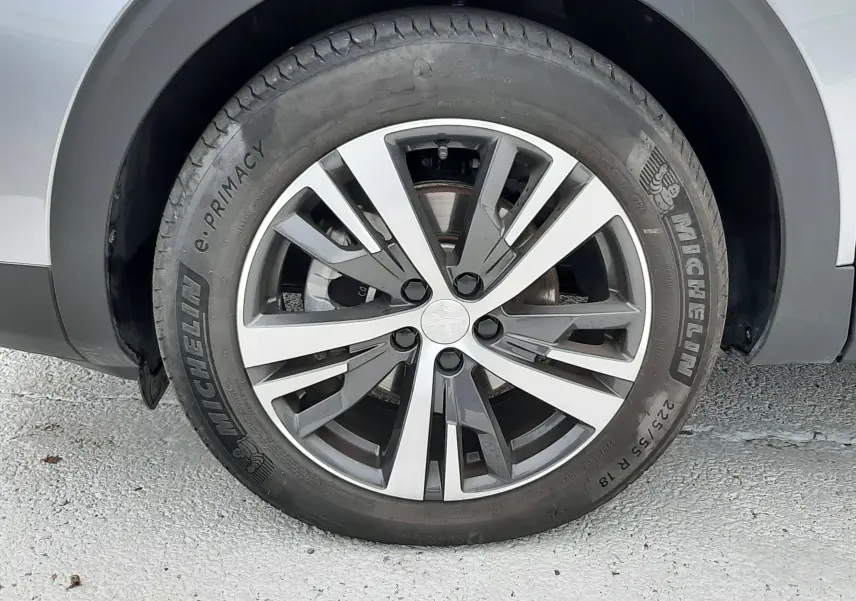 Gros plan sur la roue avant gauche du Peugeot 3008 gris Artense avec jante alliage bicolore et pneu Michelin.