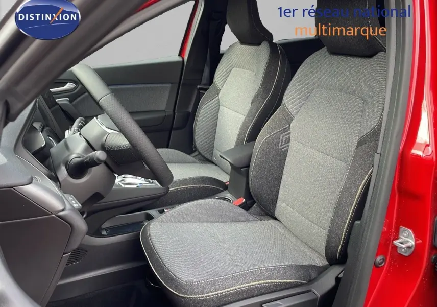 Intérieur avant du Renault Captur rouge passion, sièges tissu gris avec surpiqûres contrastées et volant visible.
