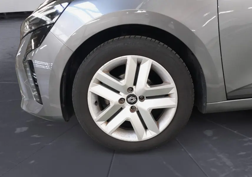 Gros plan sur la roue avant gauche d'une Renault Clio V gris schiste avec jante alliage à cinq branches.