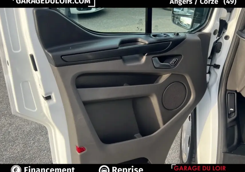 Vue rapprochée de la porte avant gauche blanche du Ford Transit Custom avec panneau intérieur noir et haut-parleur intégré.