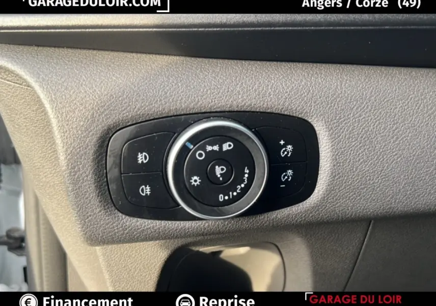 Gros plan sur le bouton de réglage des phares dans l’habitacle du Ford Transit Custom blanc, côté conducteur.