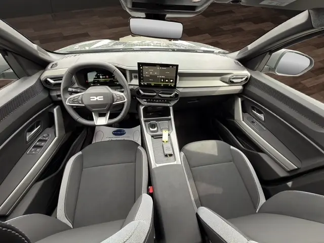 Vue intérieure avant du Dacia Bigster Journey Hybrid 155 2026, tableau de bord gris foncé avec écran tactile central et volant multifonctions.