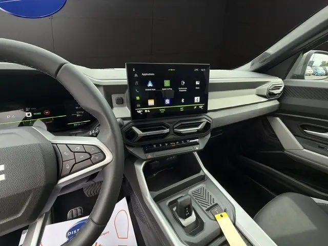 Vue intérieure côté conducteur du tableau de bord du Dacia Bigster gris foncé, avec écran tactile central et volant multifonctions.