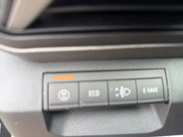 Gros plan sur les boutons de commande du tableau de bord du Dacia Bigster gris foncé, avec indicateur orange allumé.