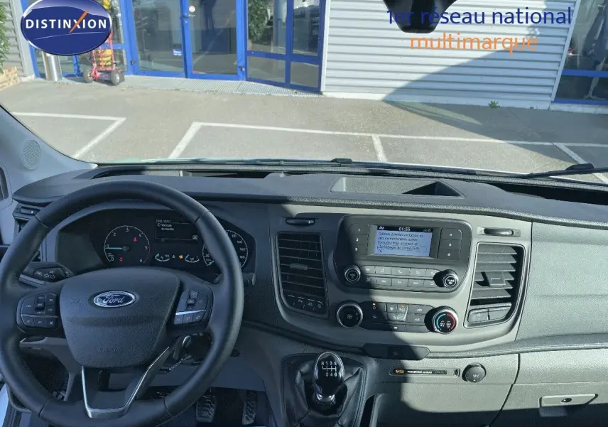 Vue intérieure du tableau de bord et volant noir du Ford Transit Fourgon blanc 2023, avec levier de vitesses manuel visible.