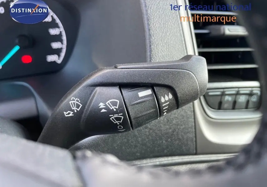 Gros plan sur la commande d'essuie-glace à gauche du volant dans le tableau de bord d'un Ford Transit blanc 2023.