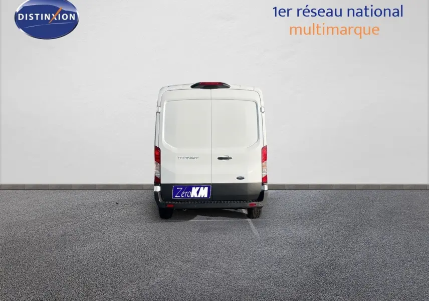 Vue arrière d'un fourgon Ford Transit blanc 2023 garé devant un mur blanc avec plaque Zero KM.