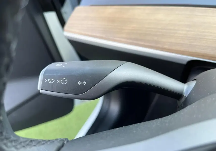 Le commodo de clignotants et essuie-glaces de la Tesla Model 3 Standard Plus RWD 2022, intérieur noir avec tableau de bord bois.