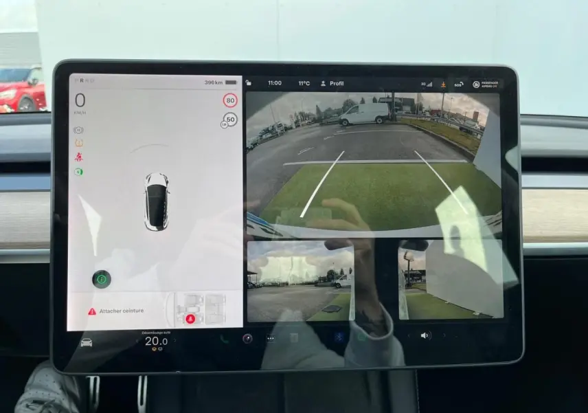 Écran tactile intérieur de Tesla Model 3 blanc 2022 montrant la caméra de recul et l'affichage des capteurs de stationnement.