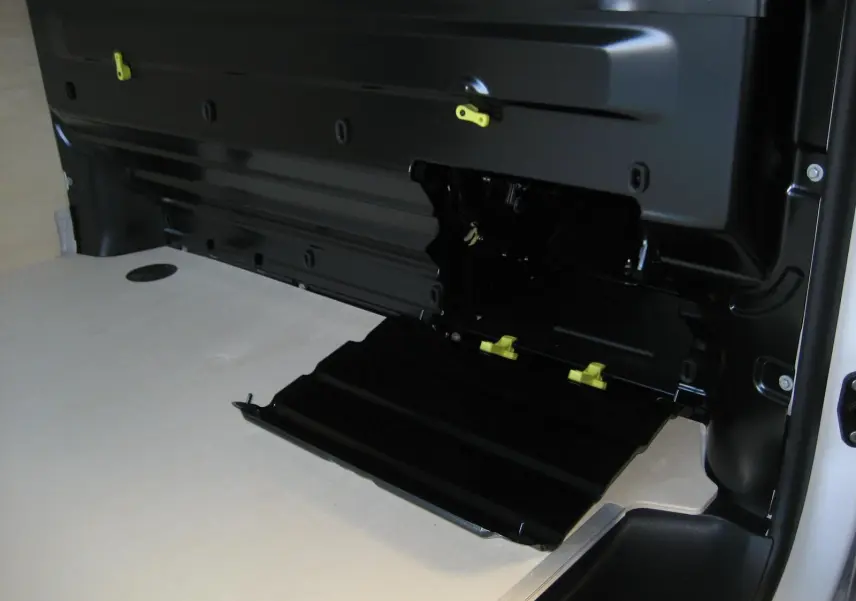 Détail intérieur du coffre du Peugeot Expert Fourgon blanc 2025, avec trappe noire ouverte et plancher bois clair.