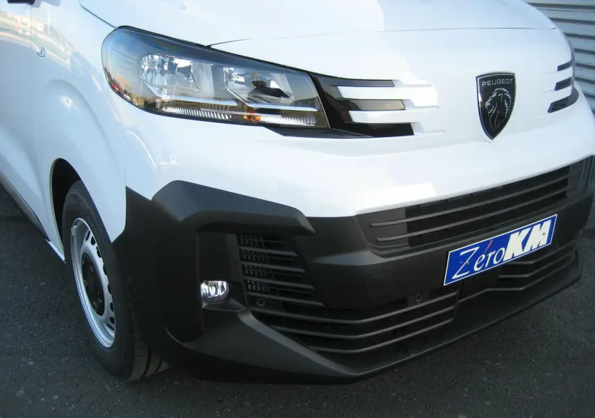 Gros plan sur l'avant droit blanc du Peugeot Expert Fourgon 2025 avec calandre noire et logo lion visible.