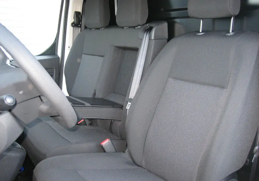 Vue intérieure rapprochée des sièges avant noirs du Peugeot Expert Fourgon avec accoudoir central et ceinture de sécurité.