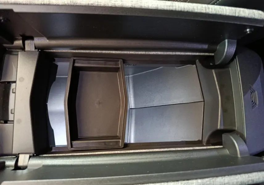 Vue intérieure du rangement central ouvert du Peugeot 3008 gris clair, montrant un compartiment modulable et un espace de chargement sans fil.