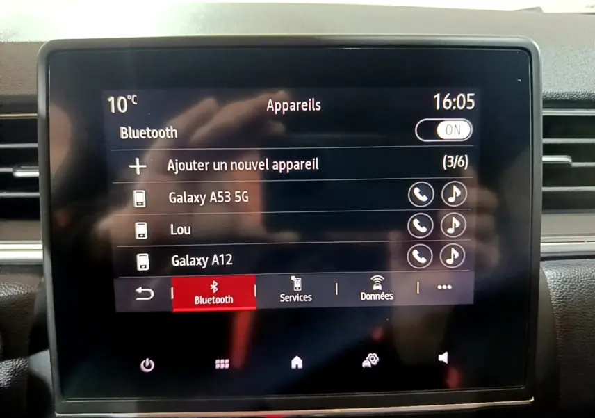 Écran tactile central du Renault Captur Intens jaune, affichant le menu Bluetooth avec plusieurs appareils connectés.