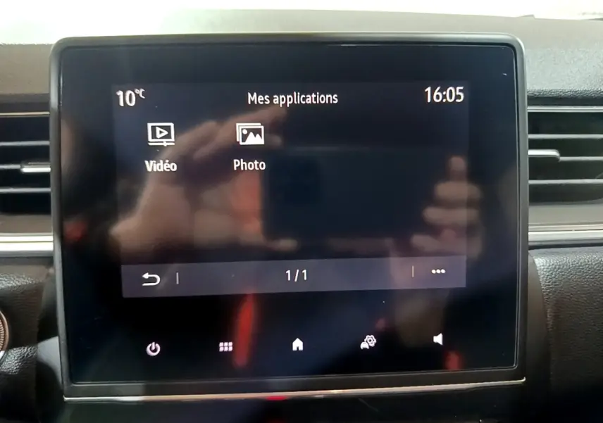 Écran tactile central du tableau de bord du Renault Captur Intens jaune, affichant les applications vidéo et photo.