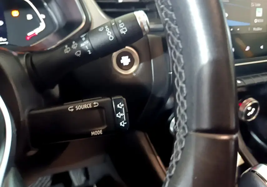 Gros plan sur le volant cuir et commandes multimédia du Renault Captur Intens jaune, tableau de bord et écran tactile visibles.