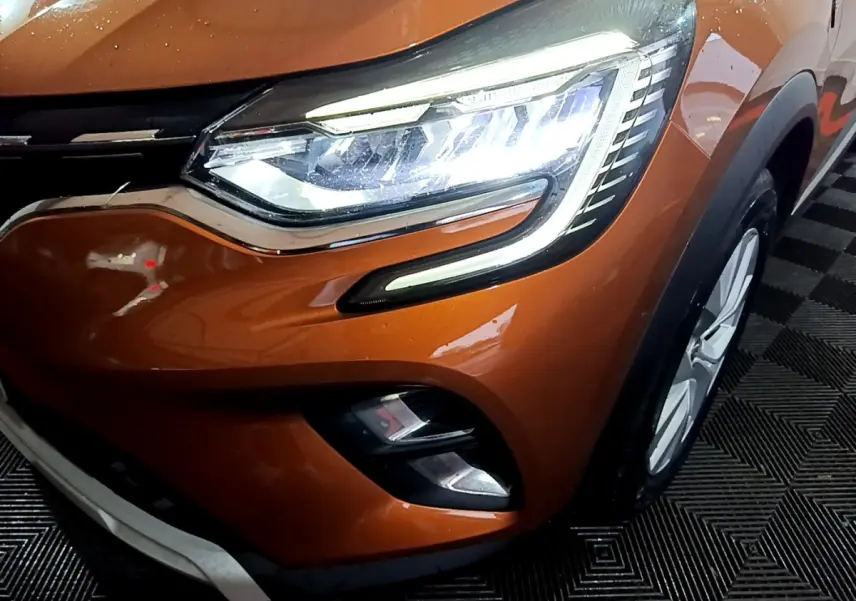 Gros plan sur l'avant droit du Renault Captur jaune, mettant en valeur le phare LED et la calandre chromée.