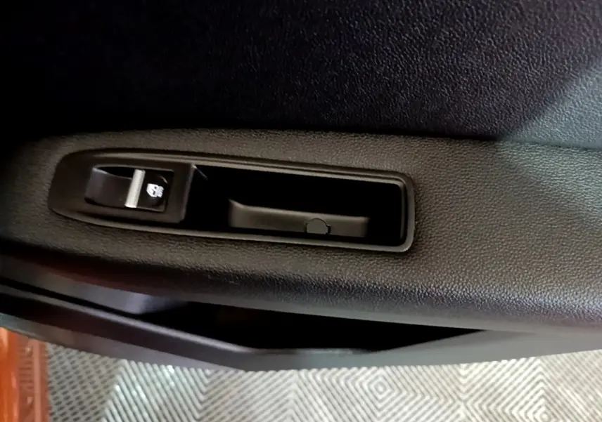 Gros plan sur la commande de verrouillage de porte noire à l'intérieur d'une Renault Captur Intens jaune, côté gauche.