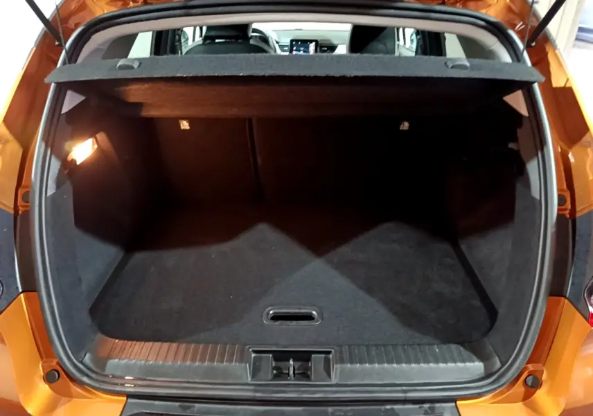 Coffre ouvert vu de l'arrière d'un Renault Captur jaune, montrant l'espace de chargement vide et la tablette cache-bagages.