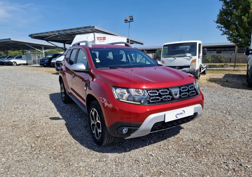 Dacia Duster rouge fusion en 3/4 avant droit, avec calandre noire et jantes alliage noires et argent.