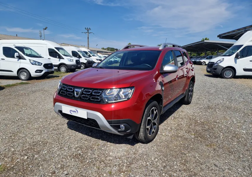 Dacia Duster rouge fusion en 3/4 avant droit, avec jantes alliage noires et coques de rétroviseurs argentées.