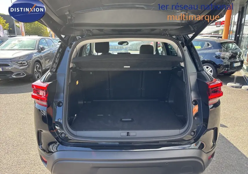 Coffre ouvert d’un Citroën C5 Aircross noir Perla Nera métal, vue arrière, montrant l’espace de chargement vide.
