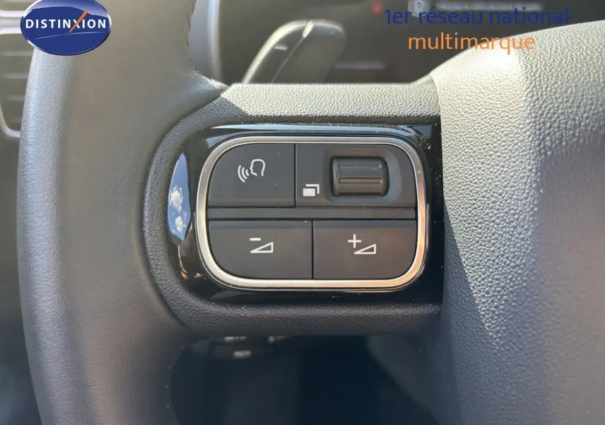 Gros plan sur les commandes gauche du volant du Citroën C5 Aircross 2025 noir Perla Nera, boutons de volume et appels.