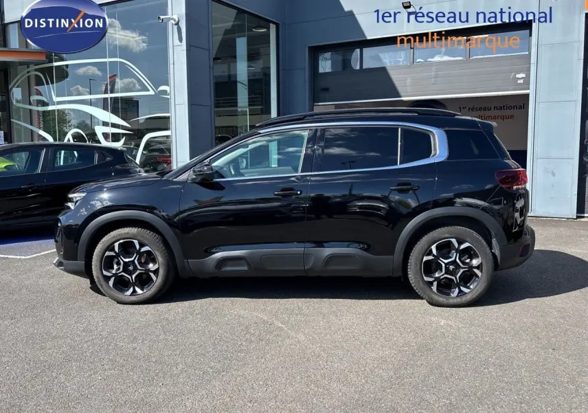 Vue de profil côté gauche d'un Citroën C5 Aircross noir Perla Nera métallisé, avec jantes distinctives et protections latérales.