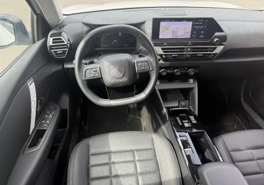 Vue intérieure avant du Citroën C4 2025 hybride, montrant le volant, tableau de bord numérique et écran tactile central.