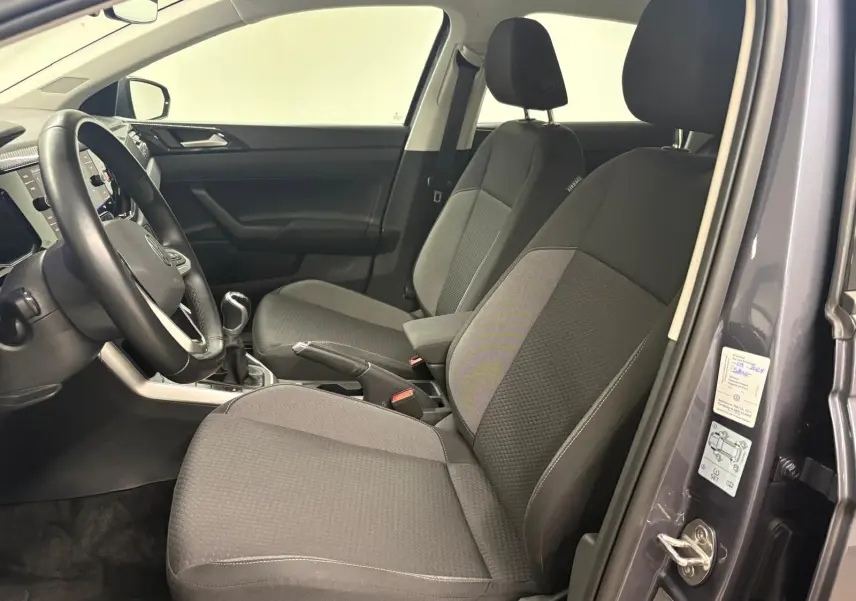 Vue intérieure côté conducteur de la Volkswagen Polo gris cendre 2024, montrant les sièges avant et la boîte manuelle.