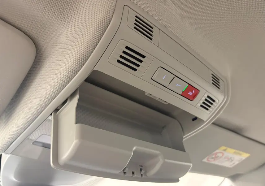 Vue intérieure du rangement lunettes ouvert au plafond d'une Volkswagen Polo gris cendre 2024, avec commandes SOS visibles.