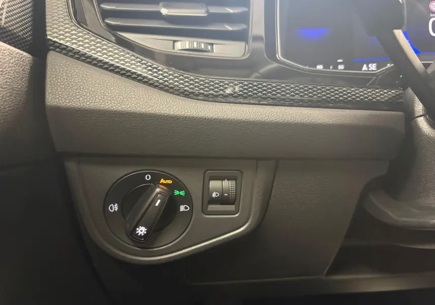 Détail du tableau de bord côté gauche de la Volkswagen Polo gris cendre 2024, avec commande d'éclairage et réglage de phares.