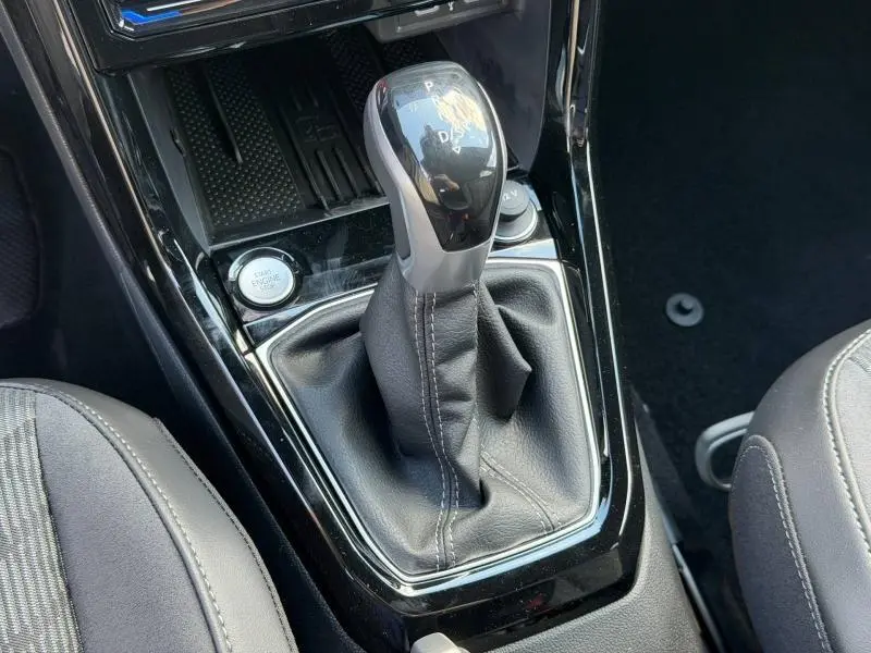Vue rapprochée du levier de vitesse automatique en cuir noir du Volkswagen T-Cross 1.0 TSI 116ch R-Line, avec bouton start/stop visible.